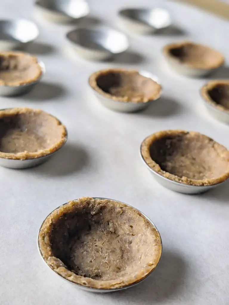 Vue de la pâte brisée aux croquettes dans des mini moules à tartelette