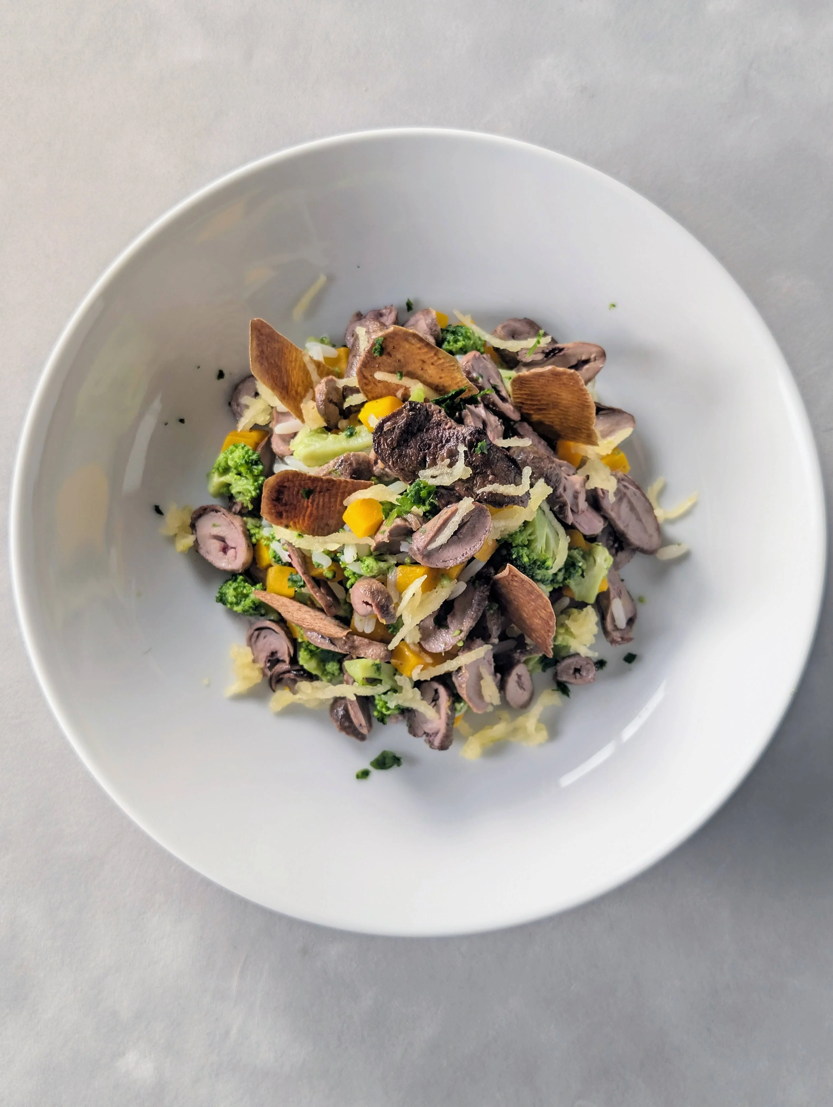 Ration ménagère pour chien au coeurs et foies de volaille, légumes et riz présentés dans une assiette blanchee et vue de dessus